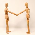 2 wooden people shaking hands